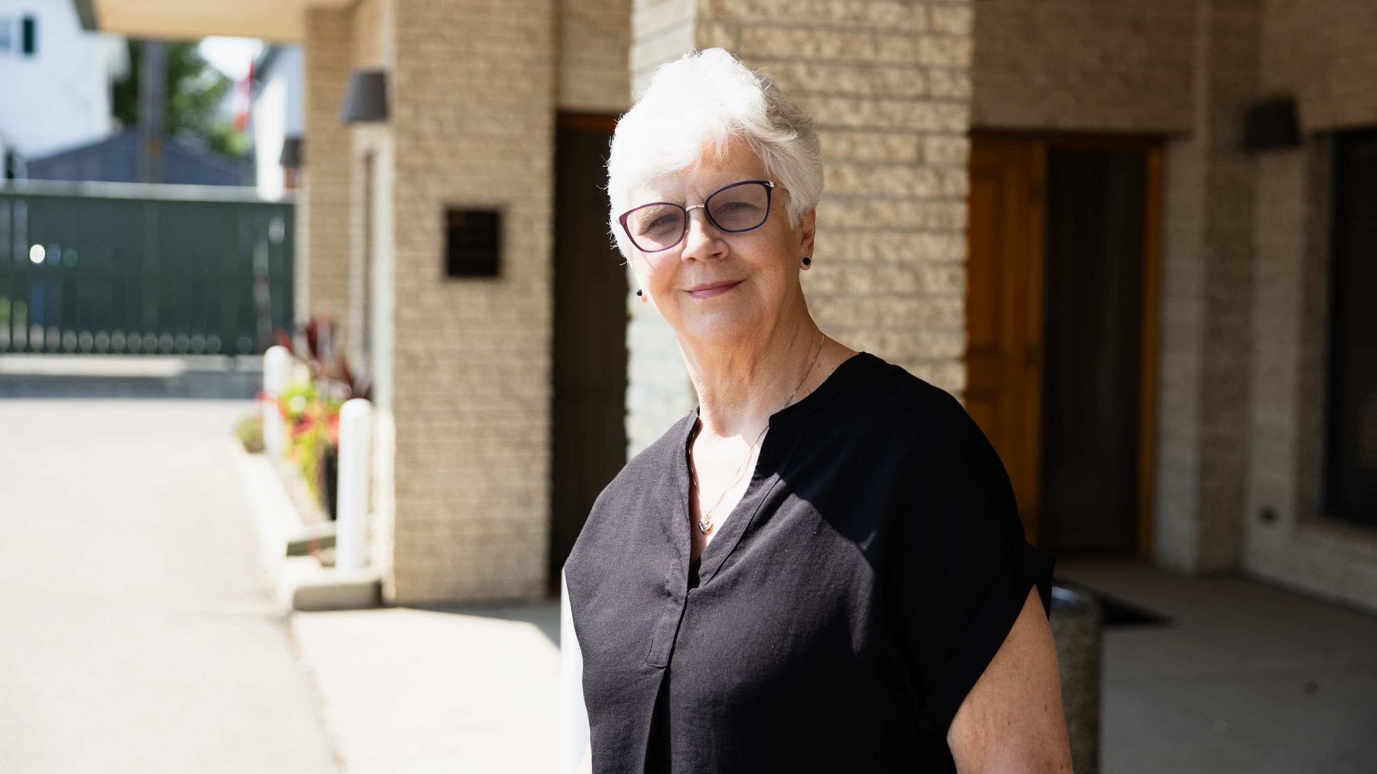 A funeral director standing outside her chapel on a bright morning