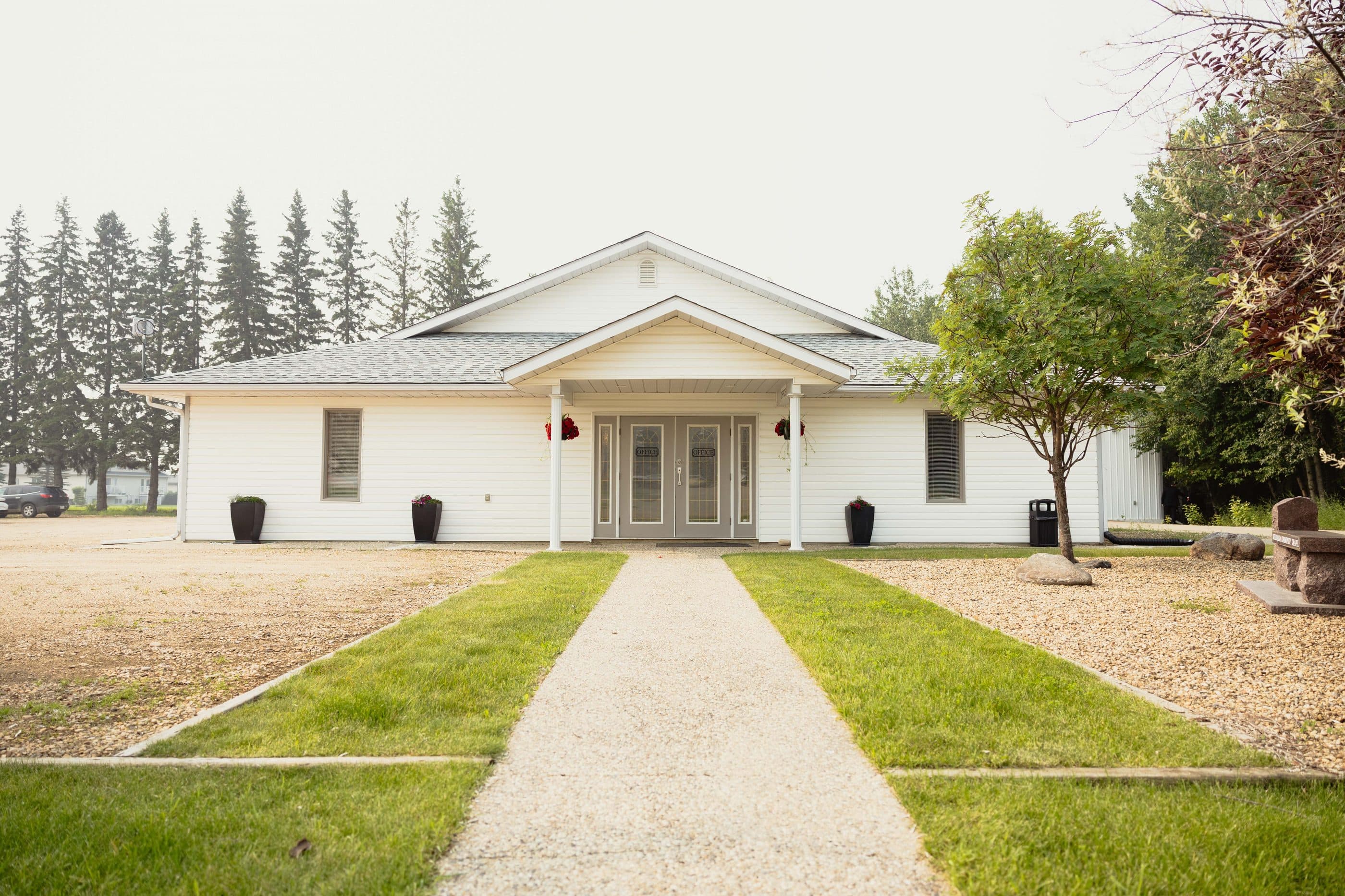 The Athabasca Community Chapel, a white building framed by evergreens