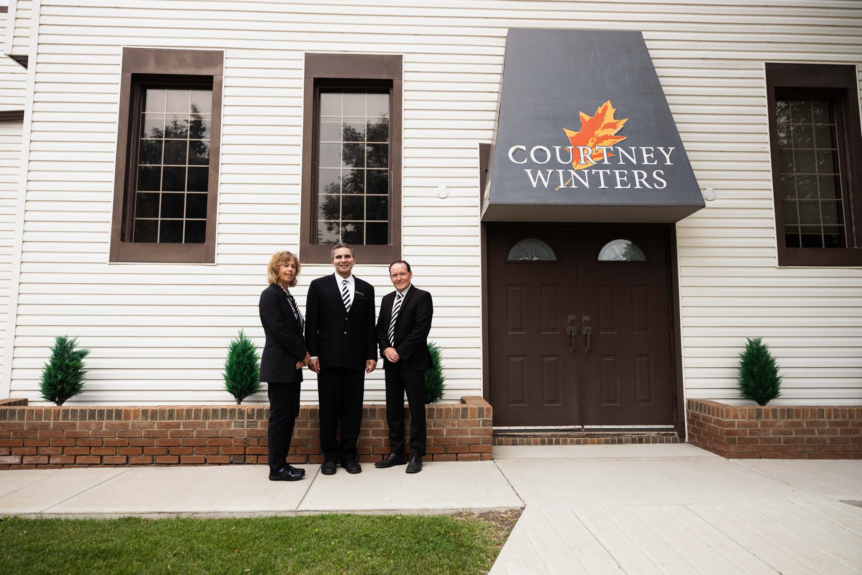 The Courtney-Winters team standing outside the funeral home entrance beneath the awning
