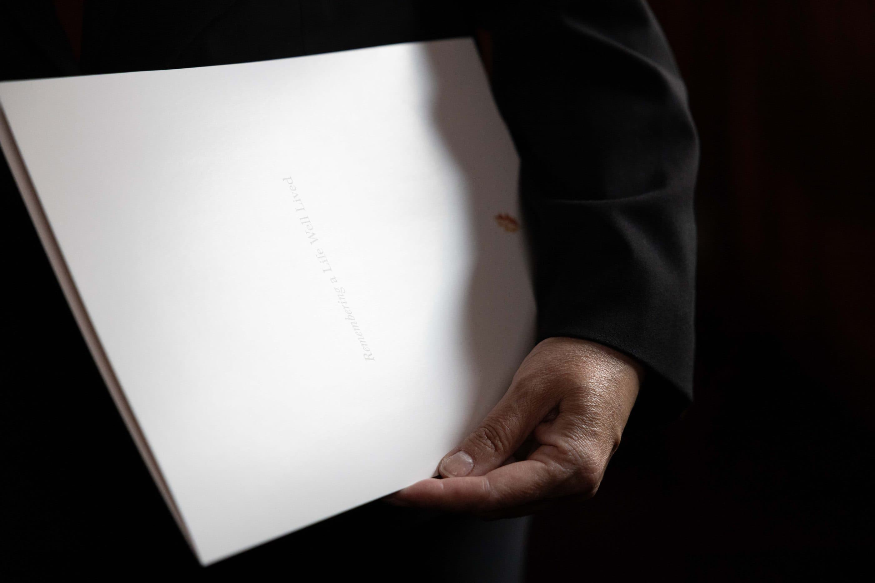 A funeral director holding a Remembering a Life Well Lived planning folder