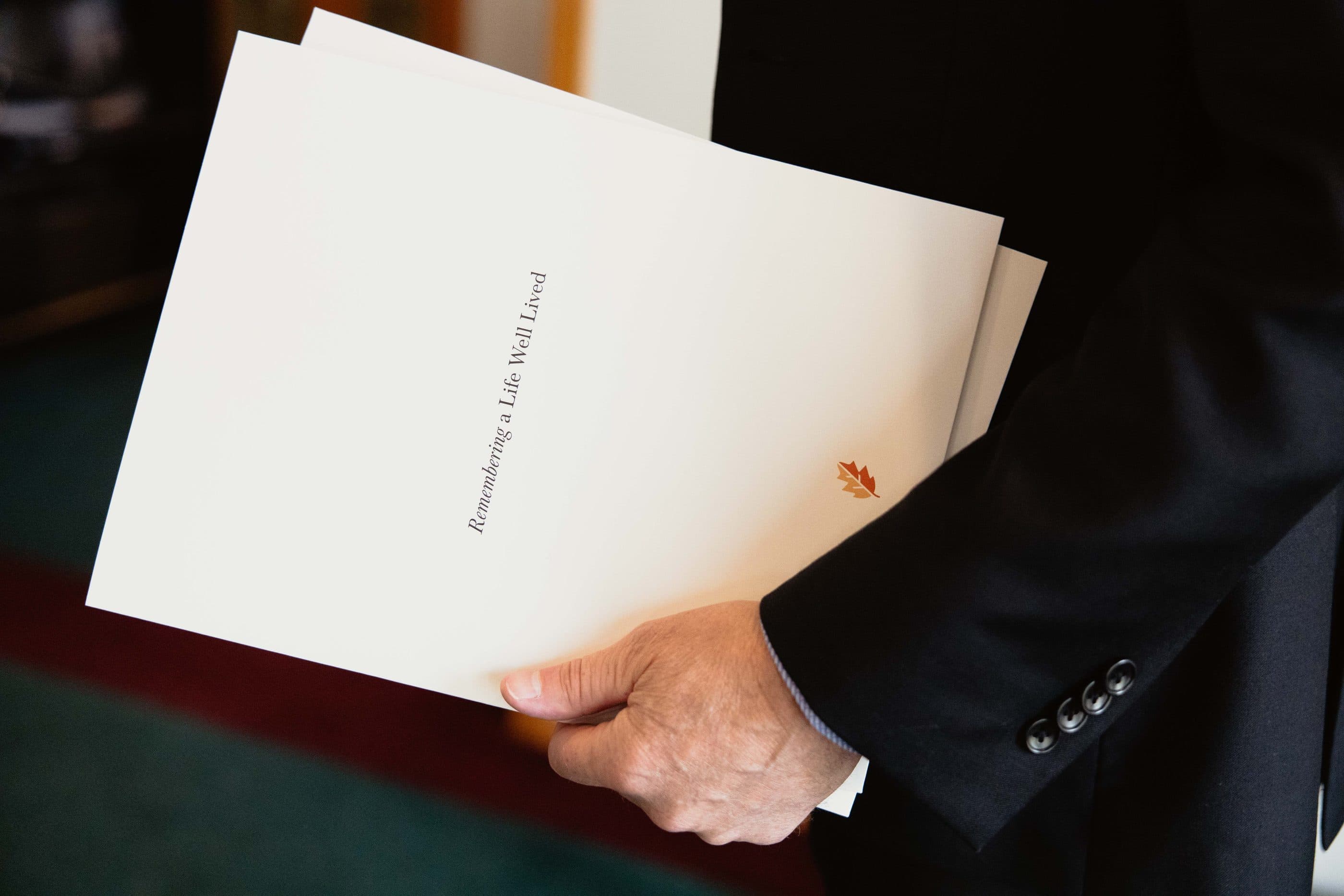 A funeral director holding a Remembering a Life Well Lived planning folder
